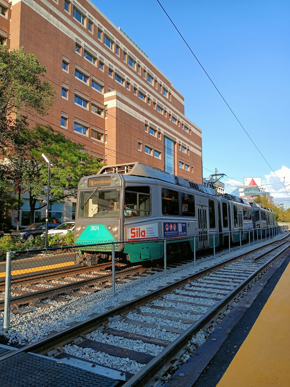 a train traveling down tracks next to a tall building