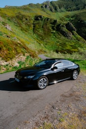 A sleek car parked on a scenic road surrounded by greenery.