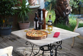 An inviting table setting outside with a steaming wood-fired pizza and a glass of red wine.