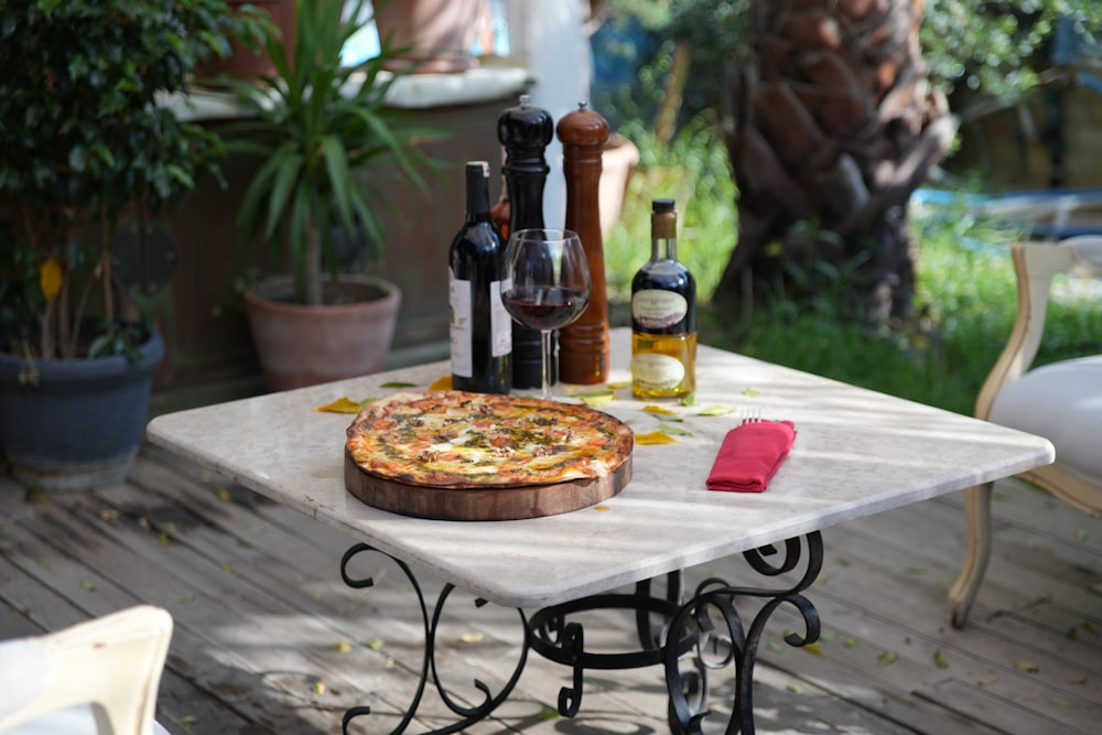 a pizza sitting on top of a table next to bottles of wine