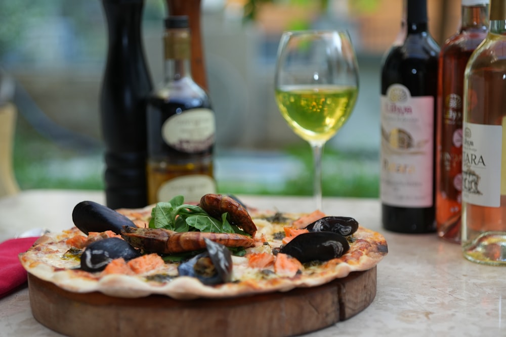 a pizza sitting on top of a table next to bottles of wine