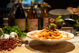a plate of pasta on a table next to bottles of wine