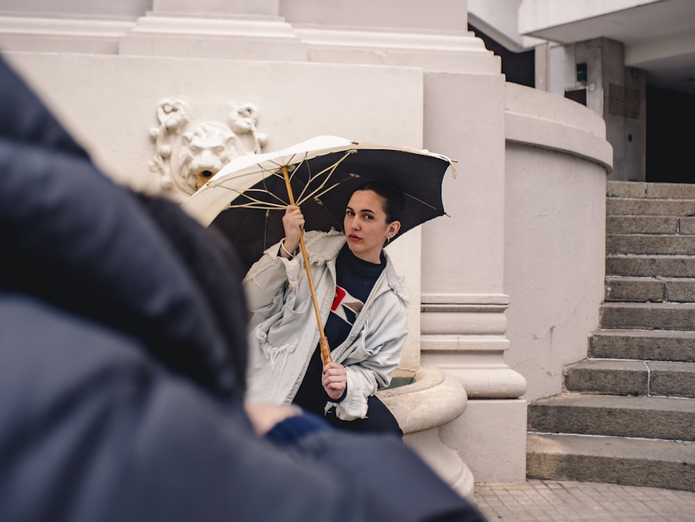 a woman sitting on the steps holding an umbrella