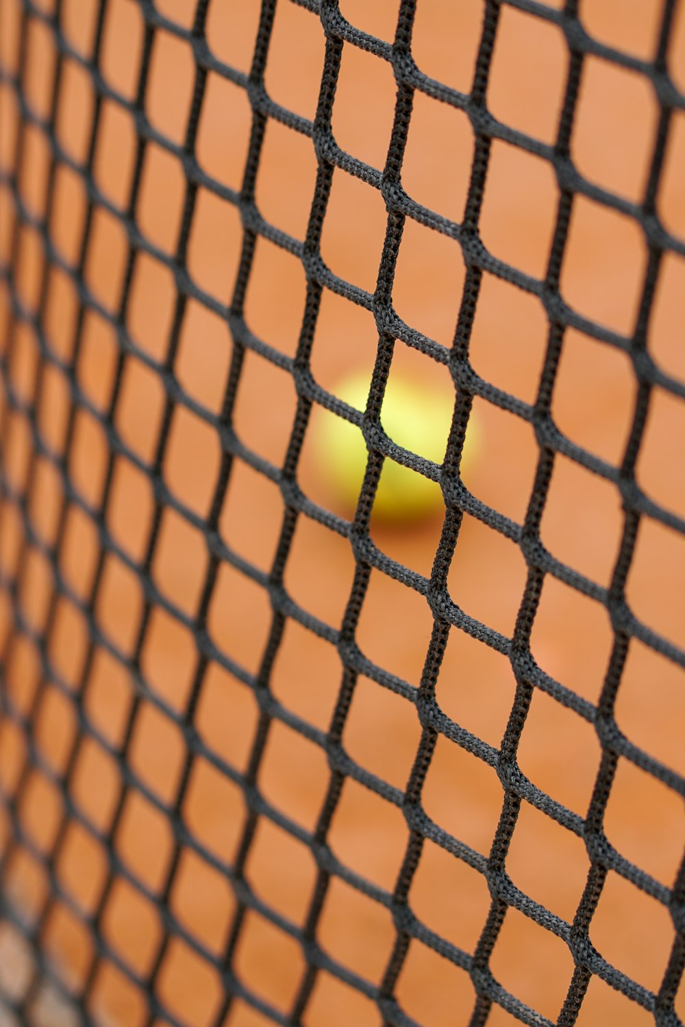 a tennis ball sitting on a tennis court net