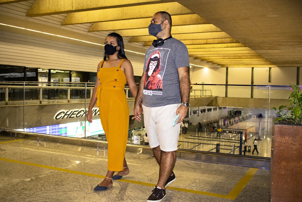 a man and a woman wearing masks walking through an airport