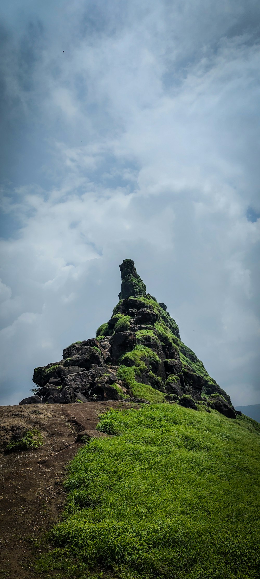 a large rock formation on top of a grassy hill
