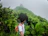 A happy traveler standing on a lush green trail in a Costa Rican cloud forest, surrounded by mist and vibrant foliage.