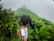 A happy traveler standing on a lush green trail in a Costa Rican cloud forest, surrounded by mist and vibrant foliage.