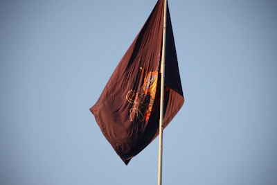 A weathered banner bearing an intricate emblem fluttering against a twilight sky.