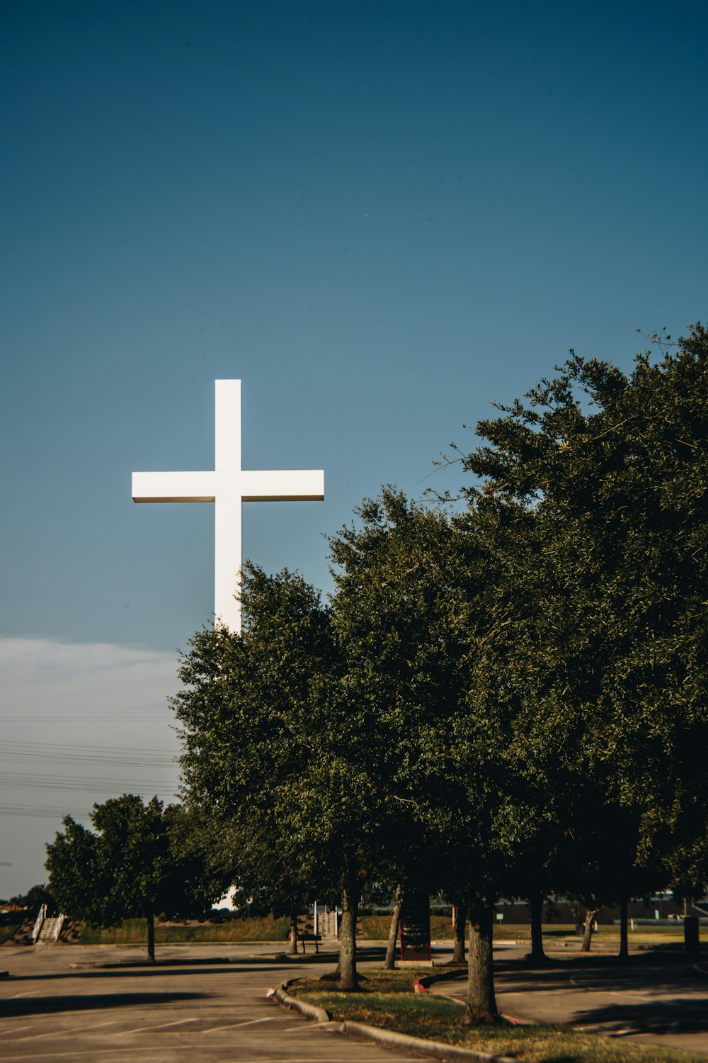 a large white cross sitting in the middle of a park