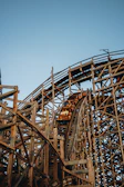 Close-up of hands tightly gripping the safety bar of a fast wooden coaster during a steep descent.