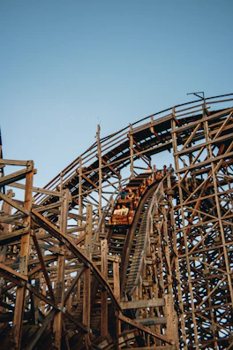 Close-up of hands tightly gripping the safety bar of a fast wooden coaster during a steep descent.
