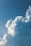A large, fluffy cloud dominates the sky, with a clear blue background that suggests a sunny day. The cloud has a soft, billowy texture and is well-lit by sunlight, highlighting its white color against the blue sky.
