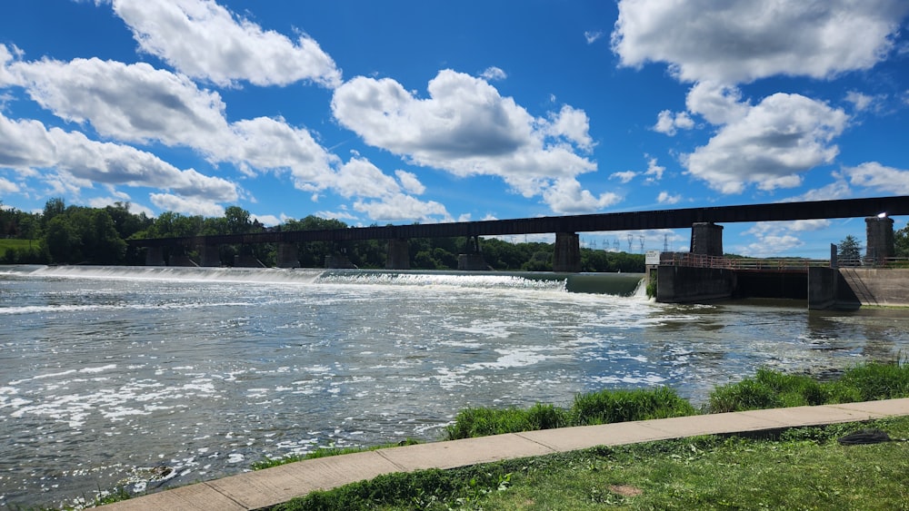 a bridge over a river with a dam in the background