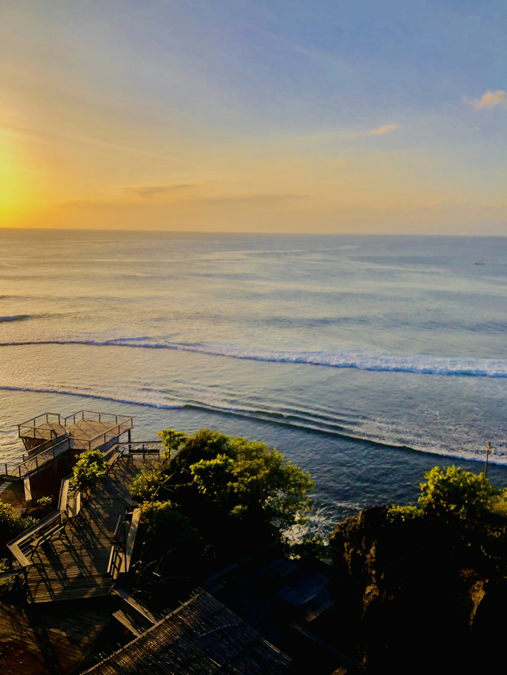 a sunset view of a beach with stairs leading to the ocean