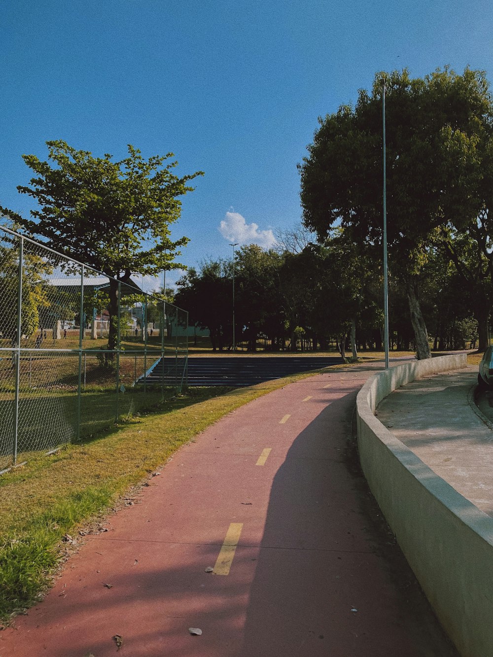 a man riding a skateboard down a street next to a fence