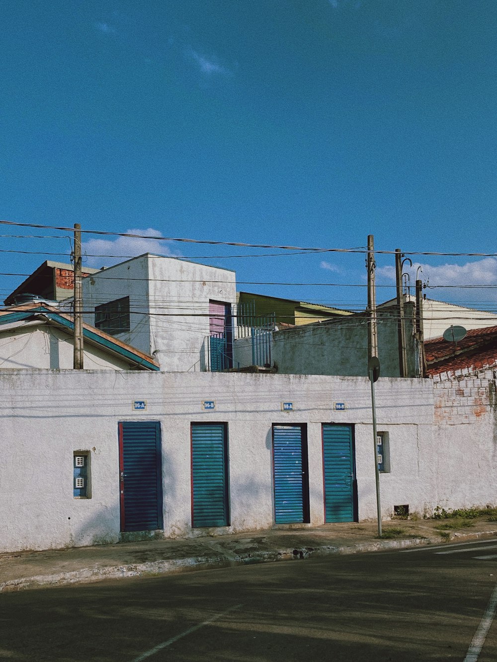 a white building with blue shutters next to a street