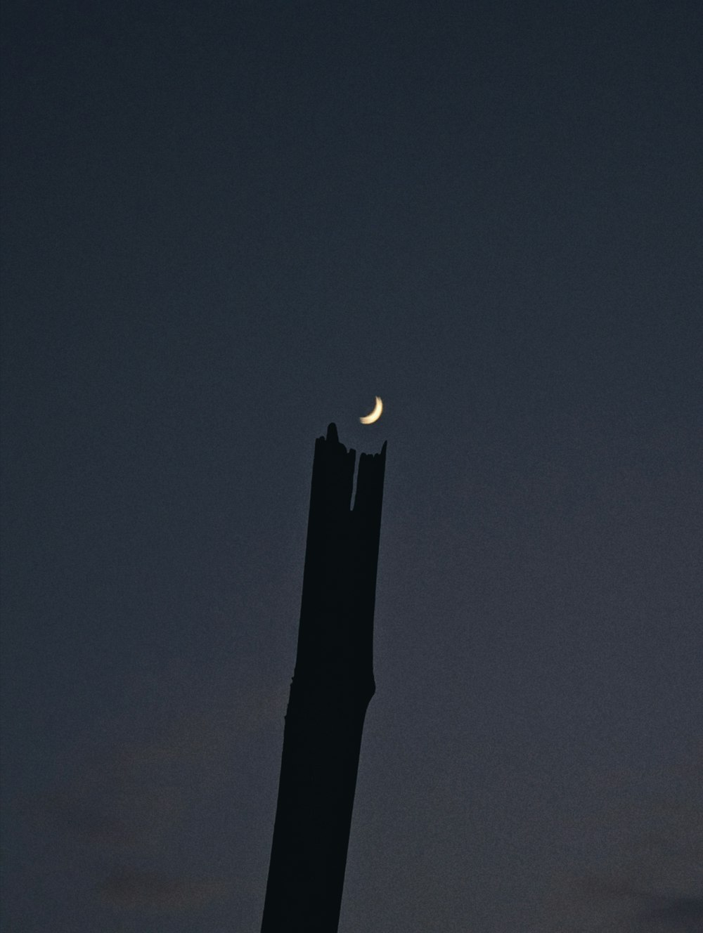 the moon is setting behind a tall tower