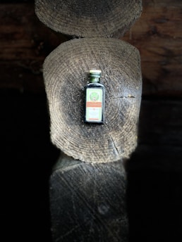 Close-up of amber cedar wood oil in a glass bottle surrounded by cedarwood logs.