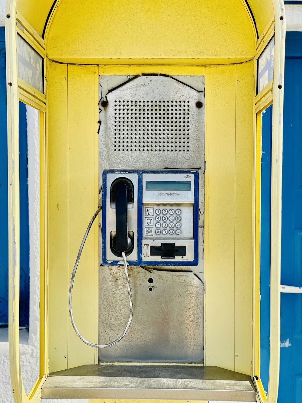 an old fashioned pay phone in front of a blue door