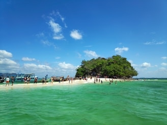 A vibrant, playful photo of young travelers enjoying a sunny beach in Lombok with bright blue sea in the background.