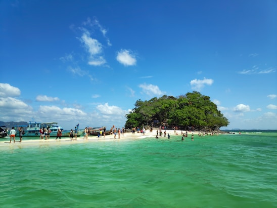 A vibrant, playful photo of young travelers enjoying a sunny beach in Lombok with bright blue sea in the background.