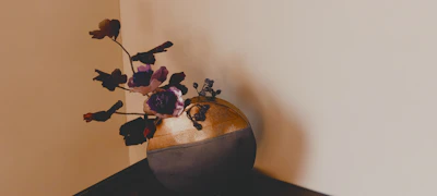 Minimalist floral urn in muted earth tones placed on a cream background with subtle shadows.