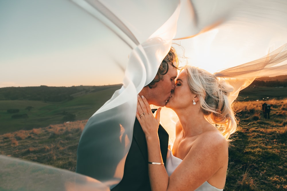 a bride and groom kissing under a veil