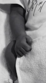 Close-up of a baby’s tiny hand resting on a soft pink blanket during a massage bébé.