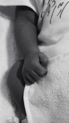 Close-up of a baby’s tiny hand resting on a soft pink blanket during a massage bébé.