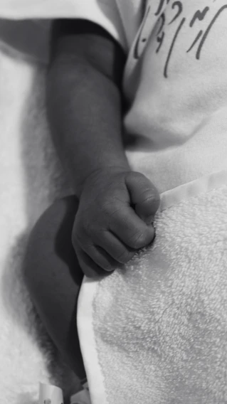 Close-up of a delicate beige baby blanket embroidered with a personalized name in elegant script.