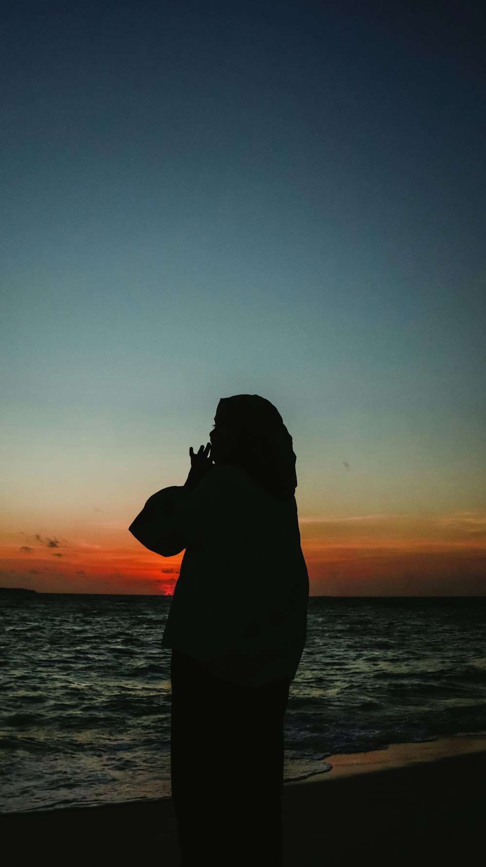 a person standing on a beach at sunset