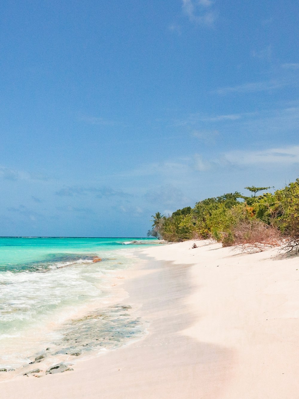 a sandy beach with clear blue water on a sunny day