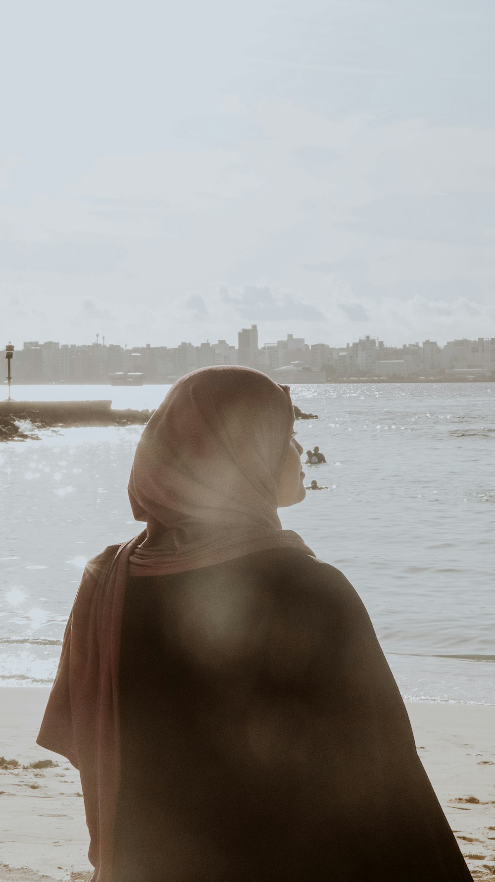 a woman standing on top of a beach next to the ocean