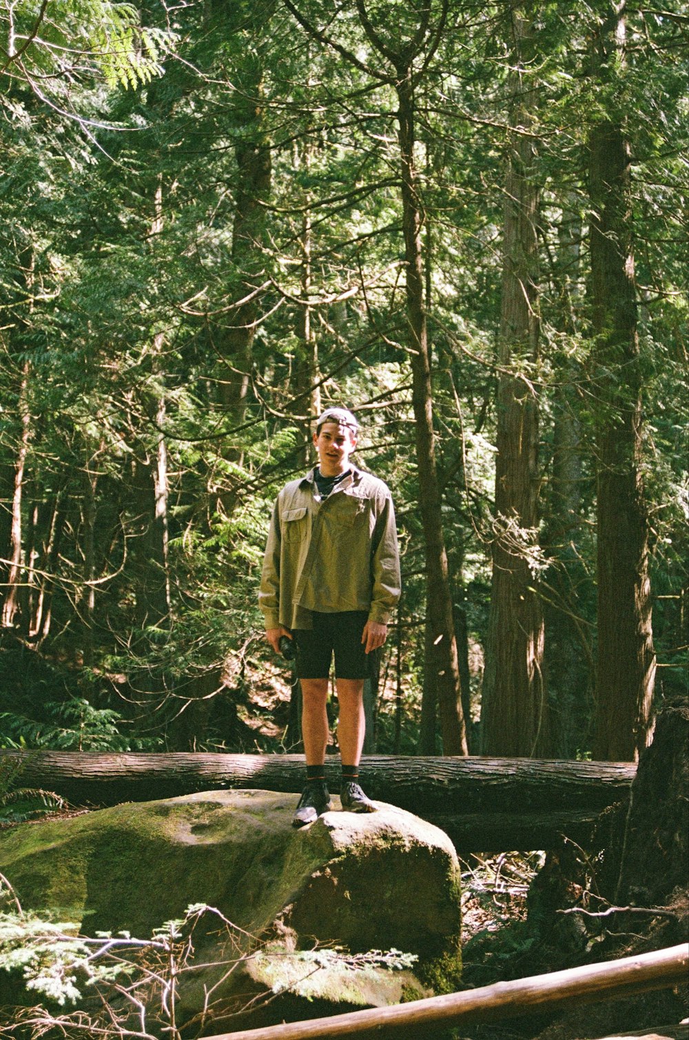a man standing on a rock in the middle of a forest