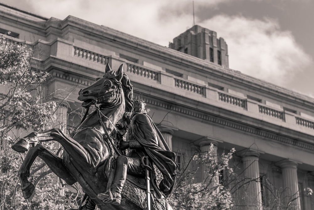 a statue of a man riding a horse in front of a building