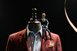 A tailored vintage blazer displayed on a sleek black mannequin against a warm ivory backdrop.