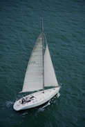 a sailboat with a white sail is in the water