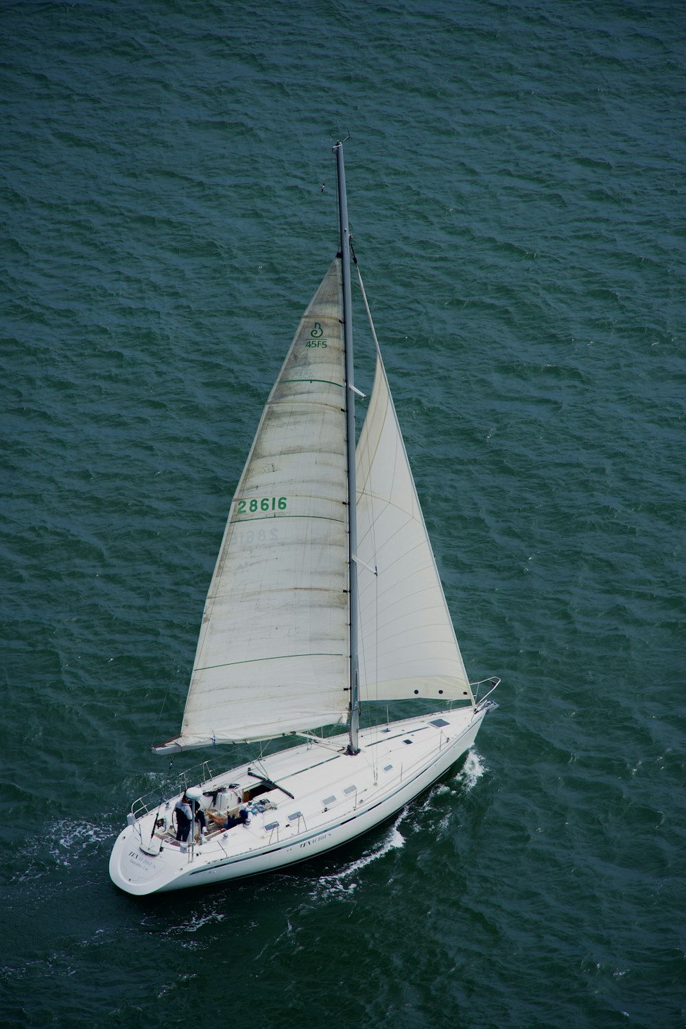 a sailboat with a white sail is in the water