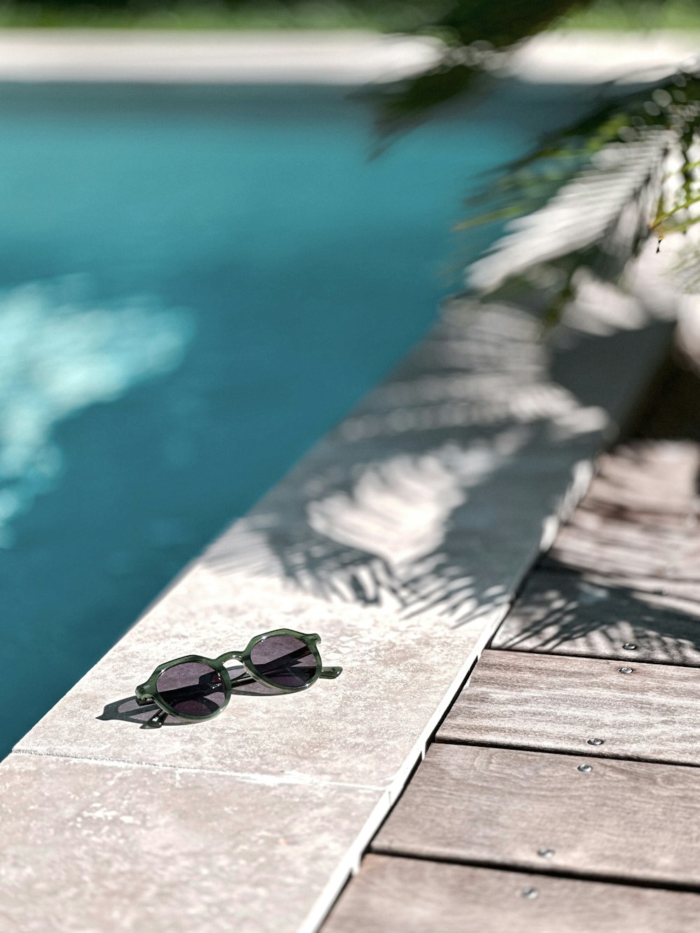 a pair of sunglasses sitting on the edge of a pool