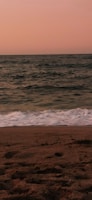 A serene beach at sunset with aqua waters and soft beige sands.