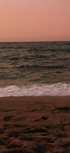 A serene beach at sunset with gentle waves and soft pastel skies.