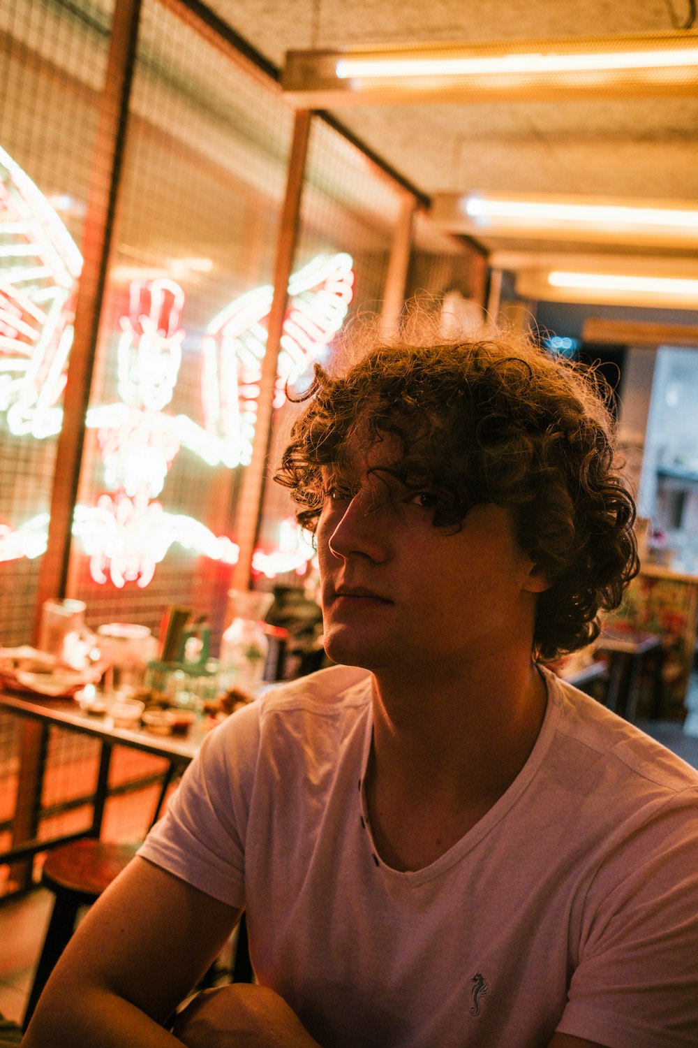 a man with curly hair sitting in front of a window