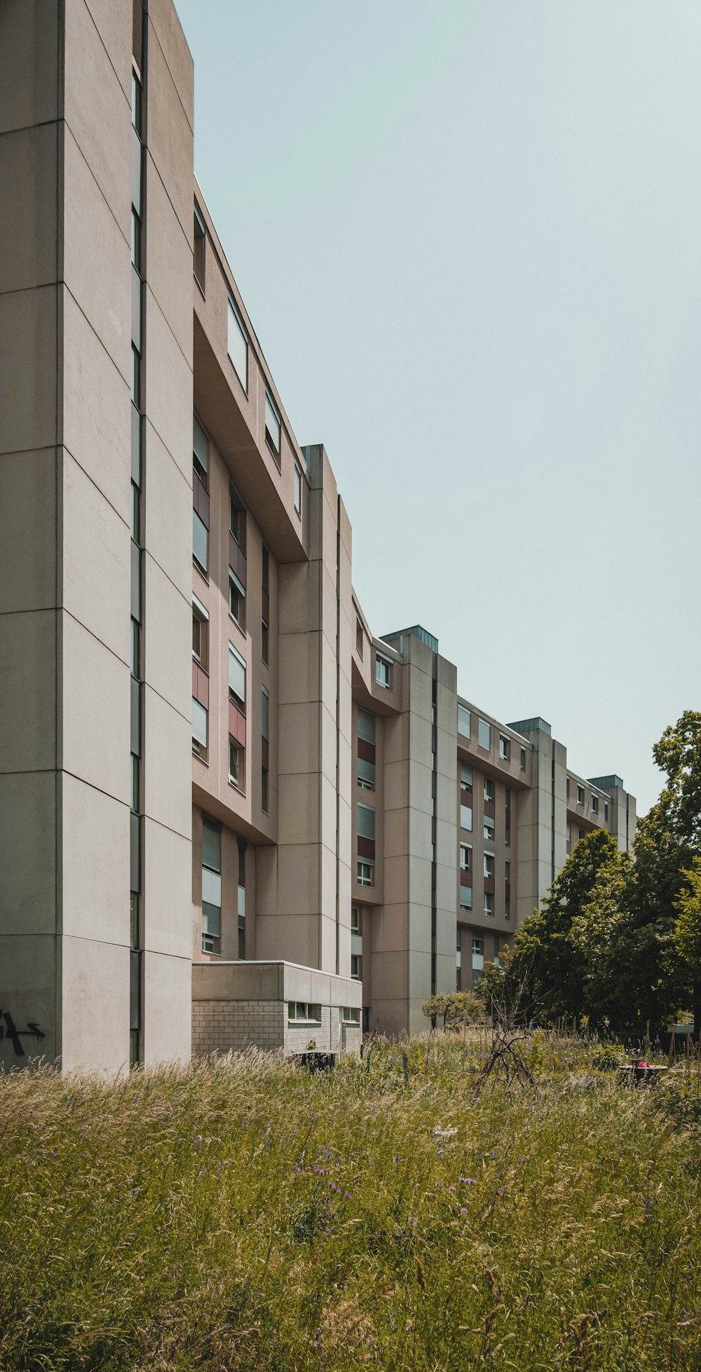 a tall building sitting on top of a lush green field