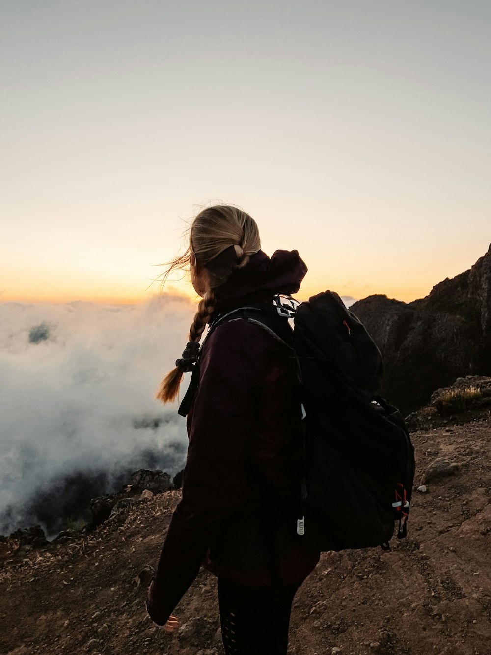 a woman with a backpack standing on top of a mountain