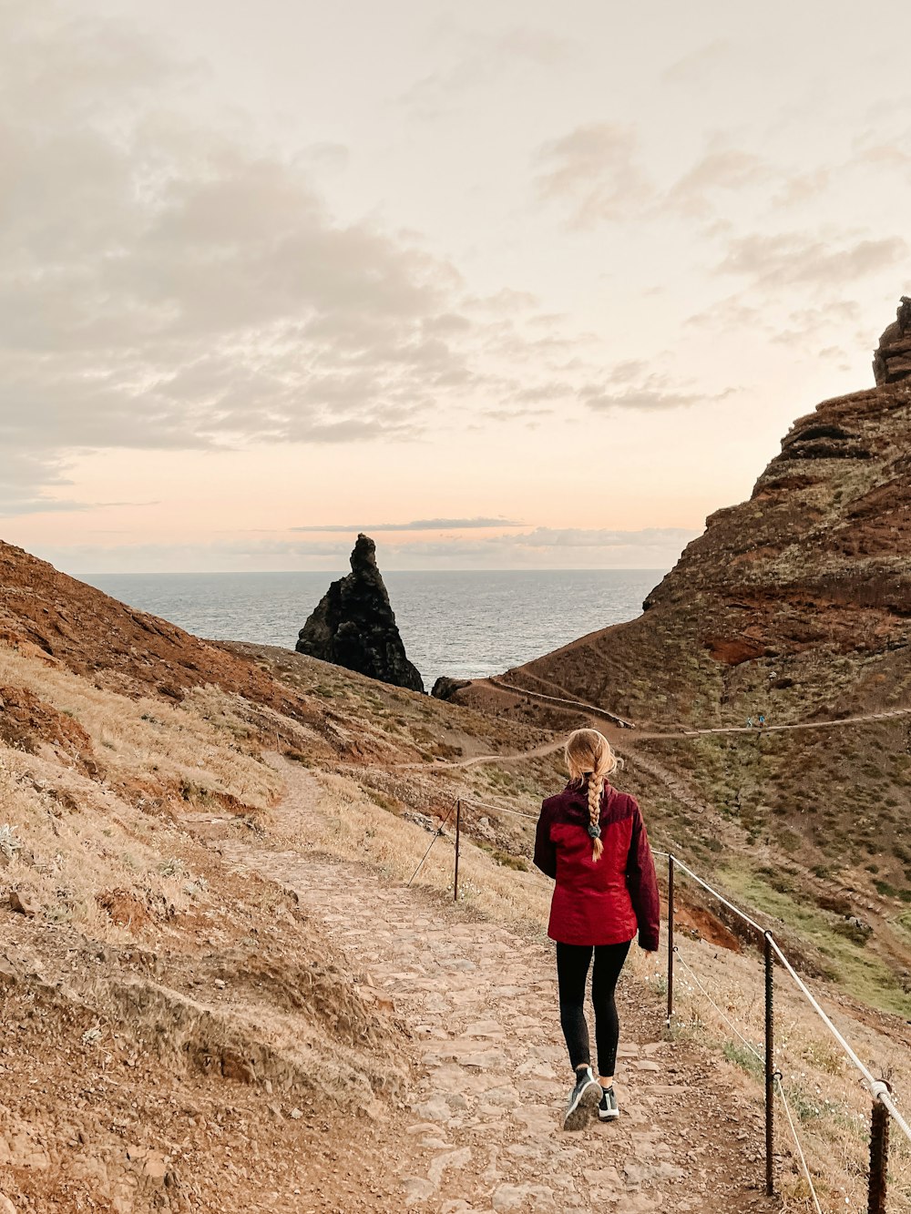 a woman in a red jacket walking up a hill