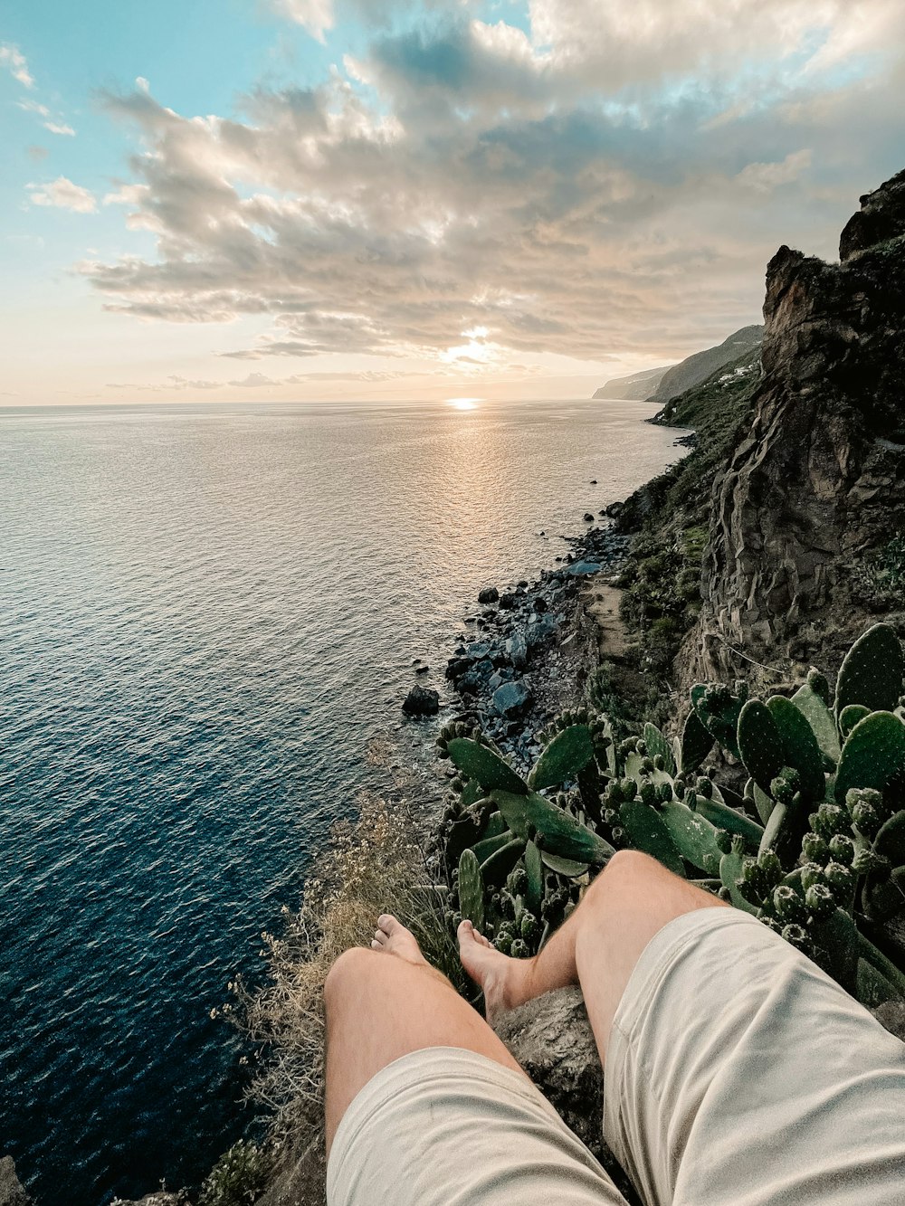 a person laying on a cliff overlooking the ocean