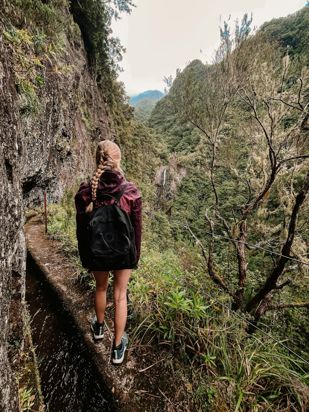 a woman with a backpack walking up a trail