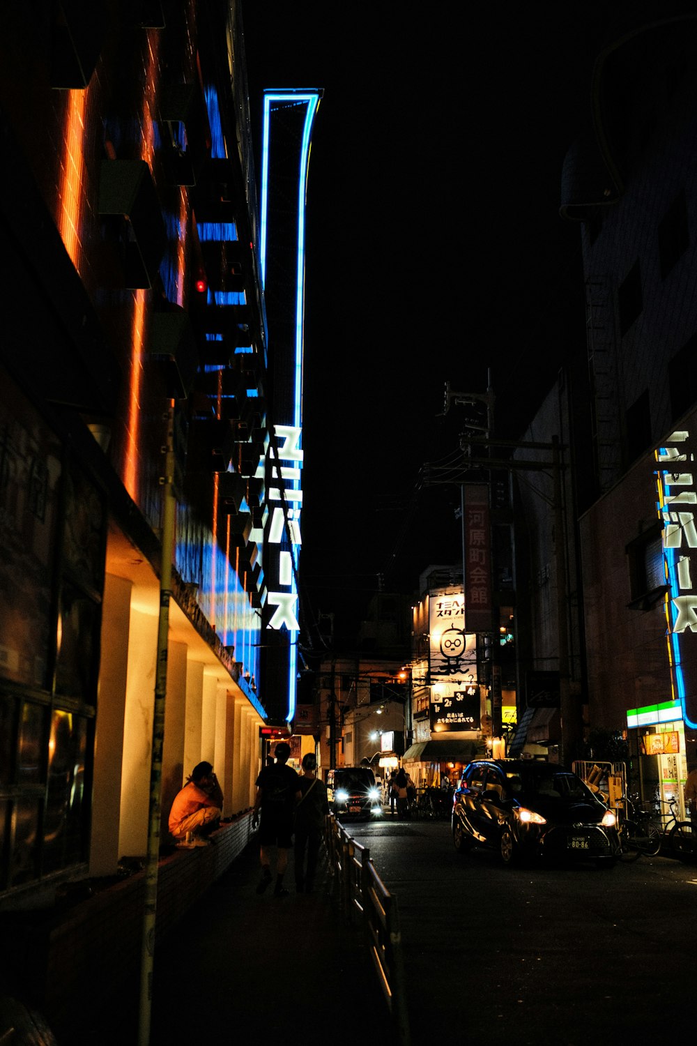 a city street at night with cars parked on the side of the road