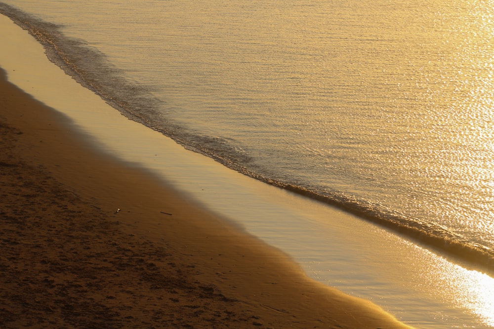 a person riding a surfboard on the beach at sunset